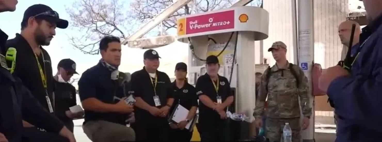 Three men standing in front of a shell gas station.